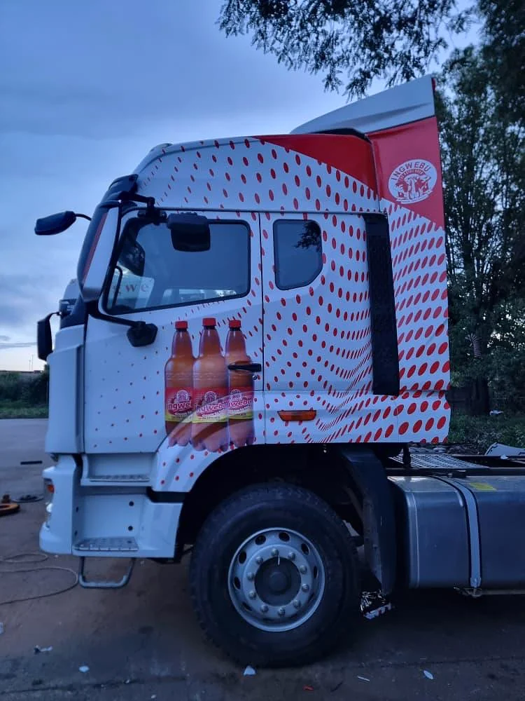 Truck cab wrapped in Ngwebu red dot graphics with product bottles